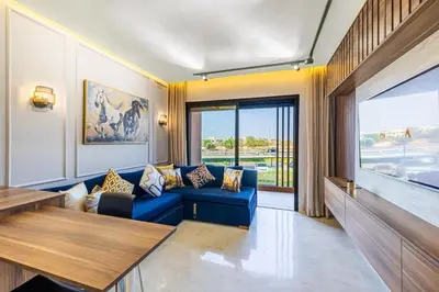 a living room with a blue couch and a large window at Noria Modern & Cozy Piscine in Marrakech