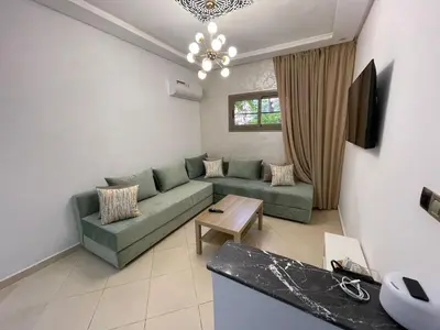 a living room with a green couch and a table at Appartement Serein 10 min jamaa el fnaaa in Marrakech