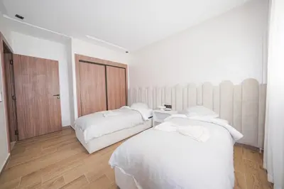 two beds in a room with white walls and wooden floors at Modern apartments, cozy residence, swimming pools in Marrakech