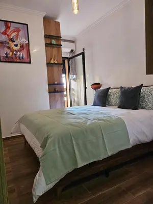 a bedroom with a bed with a green comforter at Appart Cosy et confort en plein centre Marrakech in Marrakech