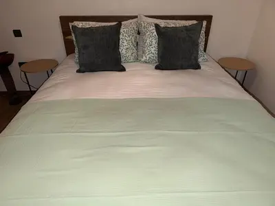 a bed with a green comforter and two pillows at Appart Cosy et confort en plein centre Marrakech in Marrakech