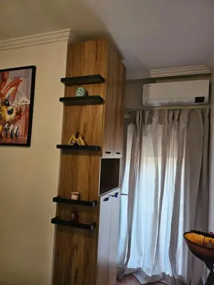 a room with a wooden book shelf next to a window at Appart Cosy et confort en plein centre Marrakech in Marrakech