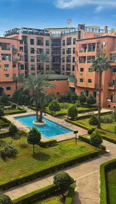 an apartment complex with a swimming pool and palm trees at appartement semlalia in Marrakech