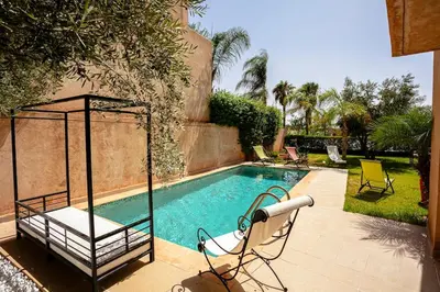 a swimming pool with two chairs and a swing at The Maison Épure - Marrakesh - Prestigia in Marrakech
