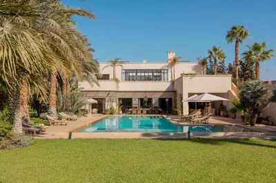 a large house with a swimming pool and palm trees at Villa Primerose in Marrakech
