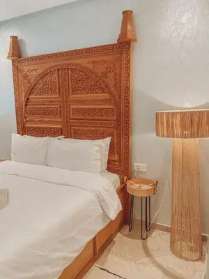 a bedroom with a large bed with a wooden headboard at Central Station Cosy Studio in Marrakech