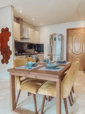 a kitchen with a wooden table with chairs and a refrigerator at Central Station Cosy Studio in Marrakech