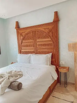 a bed with a wooden headboard in a bedroom at Central Station Cosy Studio in Marrakech