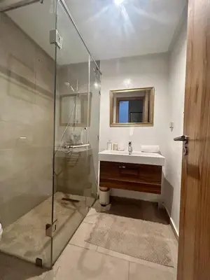 a bathroom with a glass shower and a sink at Luxueux Appartement rez-de-chaussée Noria Golf in Marrakech