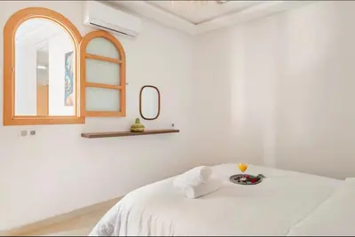 a white room with a bed and a mirror at Rental unit in Marrakech in Marrakech