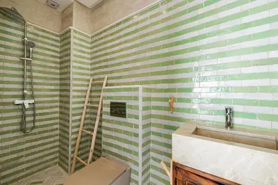 a bathroom with green and white striped walls and a sink at Riad Tigmmi - Exclusive - Pool - Free BF - 10 pax in Marrakech