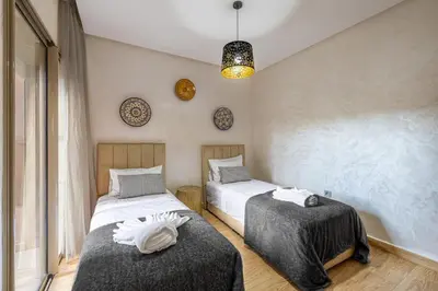 a bedroom with two beds and a chandelier at Familial appt-Prestigia- 2BR-Pool-Free parking in Marrakech