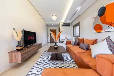 a living room with a couch and a tv at Familial appt-Prestigia- 2BR-Pool-Free parking in Marrakech