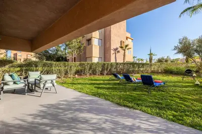 a group of chairs sitting on the grass near a building at Familial appt-Prestigia- 2BR-Pool-Free parking in Marrakech