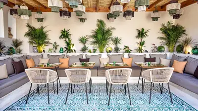 a restaurant with tables and chairs and palm trees at Riad Tamazy in Marrakech