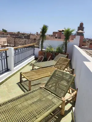 a balcony with chairs and tables on a roof at Riad in Marrakech