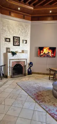 a living room with a fireplace and a tv on the wall at Luxe & calme Palmeraie terrasse piscine in Marrakech