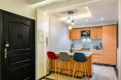 a kitchen with three bar stools and a black door at Bright & Airy Modern Flat in heart of Marrakech in Marrakech
