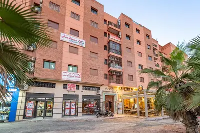 a large brick building with palm trees in front of it at Bright & Airy Modern Flat in heart of Marrakech in Marrakech