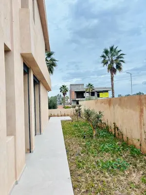 a concrete walkway next to a building with palm trees at Villa MYSK in Marrakech