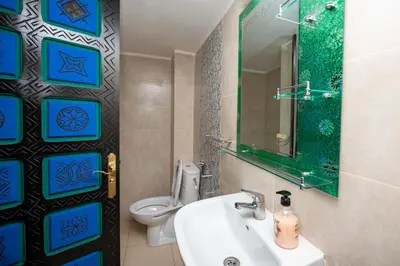a bathroom with a sink and a toilet and a mirror at Riad Blue Marrakech 4 Rooms Jacuzzi Terrace and Pool in Marrakech