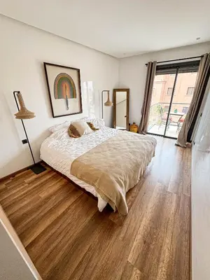 a bedroom with a large bed and a wooden floor at Appartement Haut Standing 2 Chambres avec 2 Terrasses au Centre Gueliz Marrakech in Marrakech