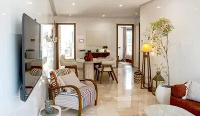 a living room with a couch and a dining room at Appartement Haut Standing 2 Chambres avec 2 Terrasses au Centre Gueliz Marrakech in Marrakech