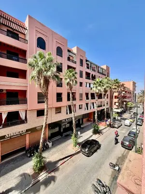 a street with palm trees in front of a pink building at City zen gueliz 1BR apartment in Marrakech
