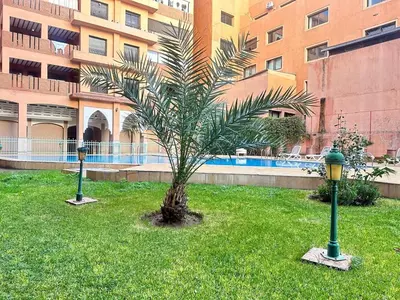 a palm tree in the grass in front of a building at Marrakech Guéliz Piscine & Terrasses Ensoleillées in Marrakech