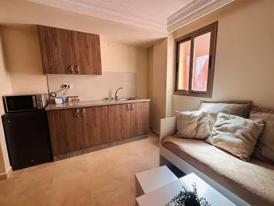 a living room with a couch and a kitchen at Suite Amethyste - Majorelle in Marrakech