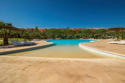 a swimming pool in a resort with chairs and trees at Oliva Hotel Condominium Marrakech in Marrakech