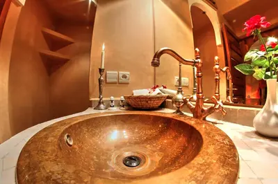 a bathroom with a copper sink with a candle at Dar Tasnime in Marrakech
