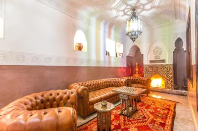 a living room with leather furniture and a fireplace at Riad Lamya Marrakech in Marrakech