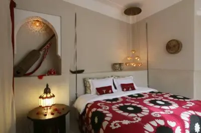 a bedroom with a red and white bed and a table at Riad Dar Ayur in Marrakech