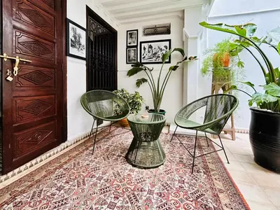 two chairs and a table in a room with plants at Riad Argan in Marrakech