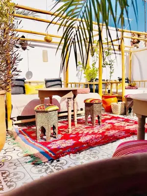 a room with a table and two stools on a rug at Riad Argan in Marrakech