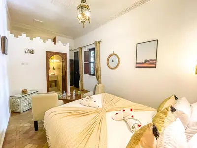 a bedroom with a bed and a table in it at Riad des Lys in Marrakech