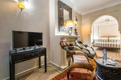 a living room with a television and a table and chairs at Riad Boustane & SPA in Marrakech