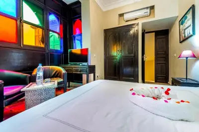 a bedroom with a bed and a room with stained glass windows at Riad Boustane & SPA in Marrakech