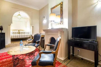 a living room with a television and a table and chairs at Riad Boustane & SPA in Marrakech