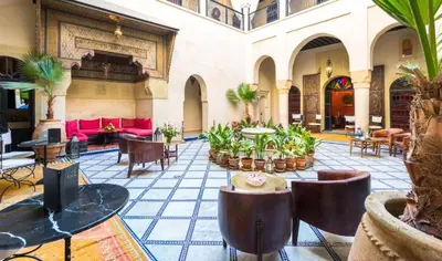 a large lobby with tables and chairs and plants at Riad Boustane & SPA in Marrakech