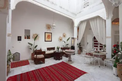 a living room with white walls and a red rug at Riad Morocco Sky in Marrakech