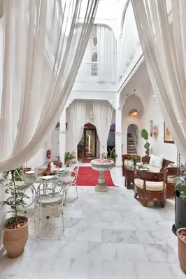 a large living room with white curtains and tables at Riad Morocco Sky in Marrakech