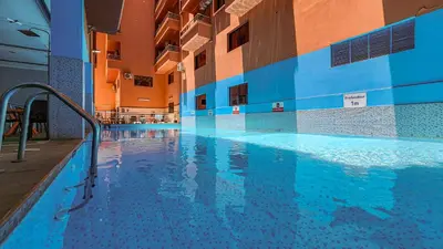 a large swimming pool in a building with blue tiles at Hôtel Les Ambassadeurs in Marrakech