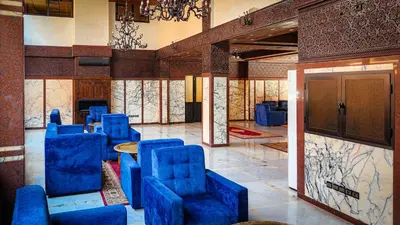 a room with blue chairs and a table in a building at Hôtel Les Ambassadeurs in Marrakech