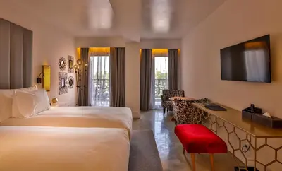 a hotel room with two beds and a desk with a television at 2Ciels Boutique Hôtel in Marrakech