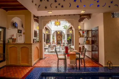 a dining room and living room with a table and chairs at Riad Sun of Kech in Marrakech