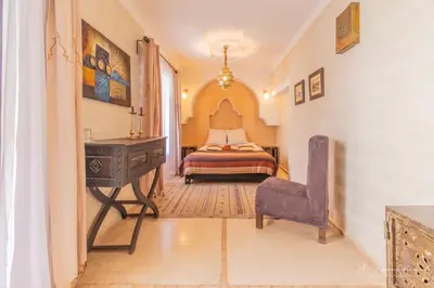 a bedroom with a bed and a desk and a chair at Riad Dar El Masa in Marrakech