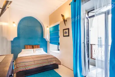 a bedroom with a bed and a desk and a window at Riad Dar El Masa in Marrakech