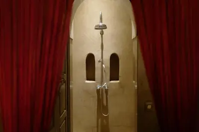 a bathroom with a shower in a room with red curtains at Riad Noir d'Ivoire in Marrakech
